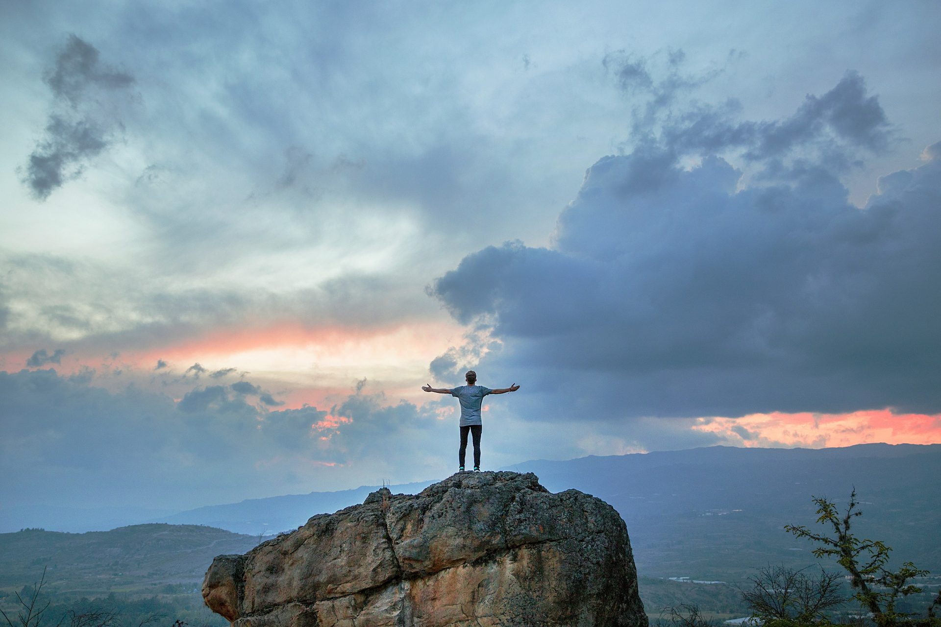 Man standing on rock, arms wide open.