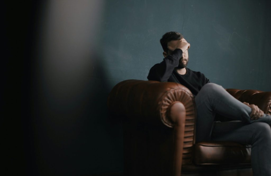 Man sitting alone, covering his face.