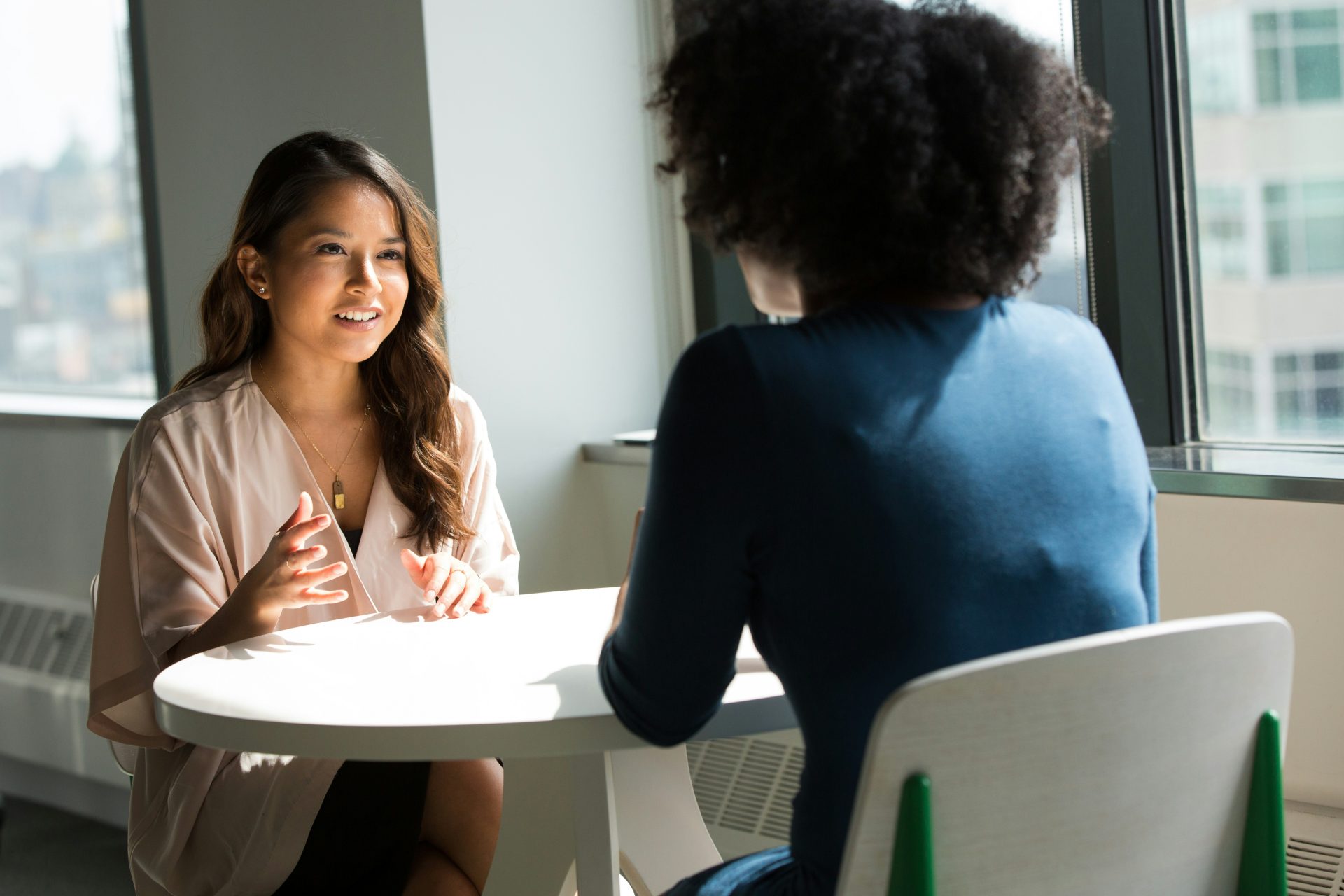 Two women talking in a bright office.