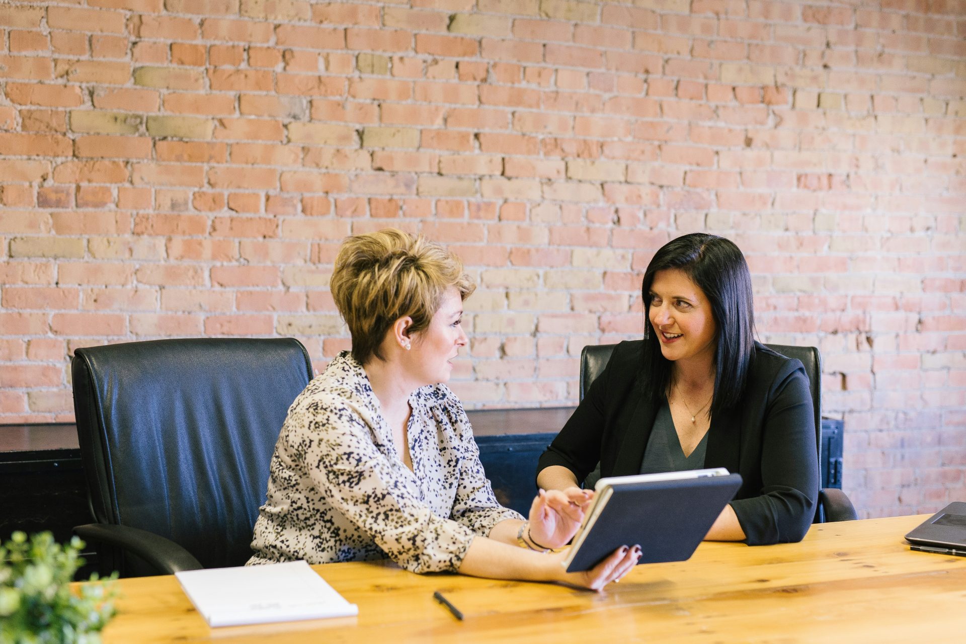 Two women discussing work in office setting.