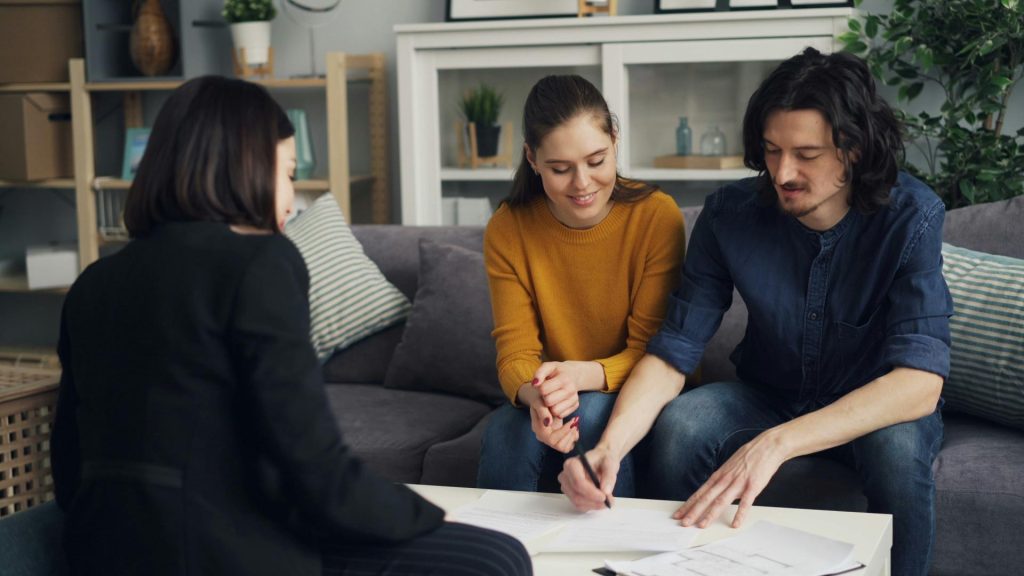 Couple signing paperwork with financial advisor.