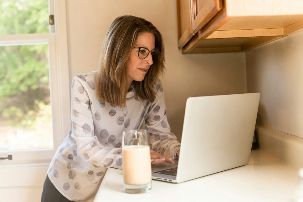 Woman using a laptop in home kitchen.